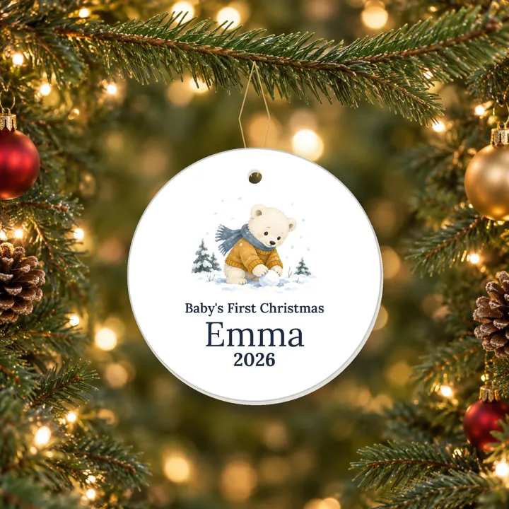 Ceramic Baby's First Christmas 2026 ornament with a winter bear and a sample name, hanging on a tree